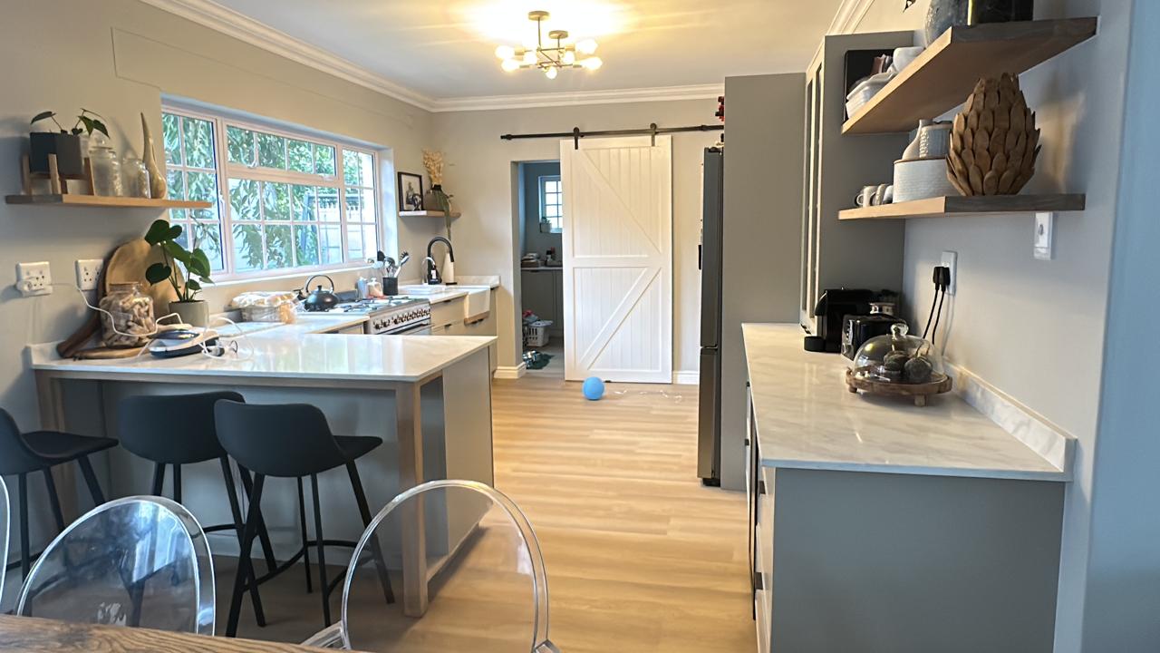 Renovated kitchen with marble worktops, timber floating shelves and barn door
