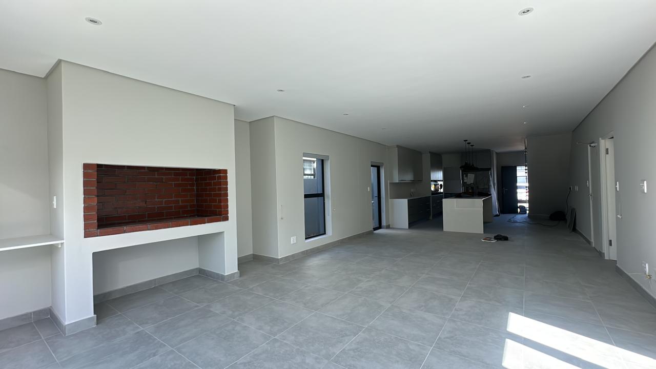 Finished open-plan living, kitchen and built-in braai with large-format tiled floor