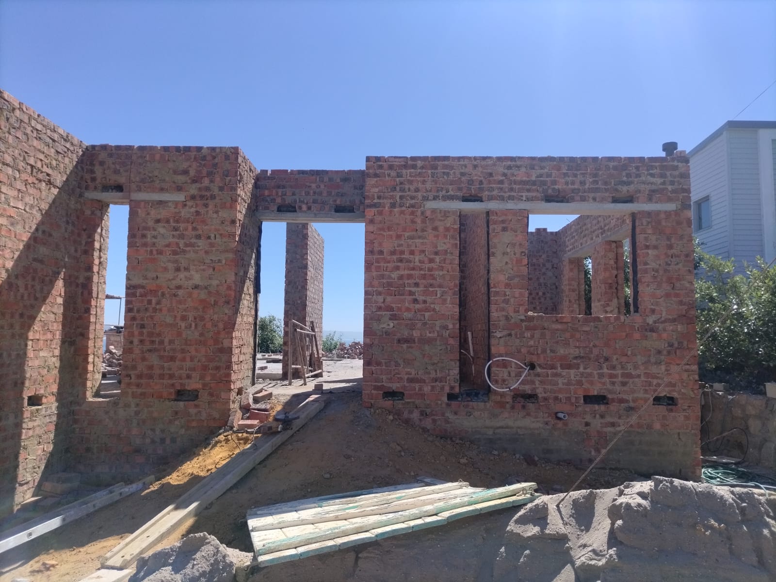 Facebrick shell with door and window openings framed, sea view beyond